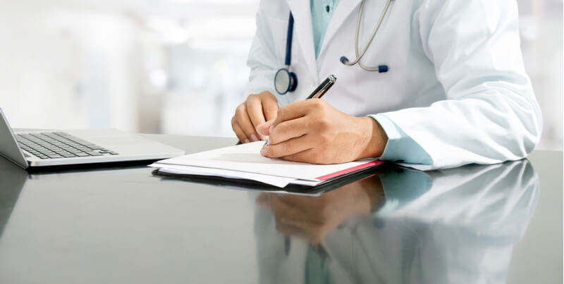 Un doctor escribiendo una informe medico.